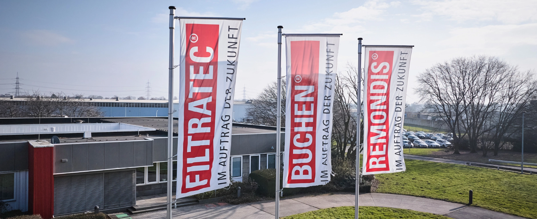 A company building with three FILTRATEC, BUCHEN and REMONDIS flags and the ‘Im Auftrag der Zukunft’ slogan on the business premises.