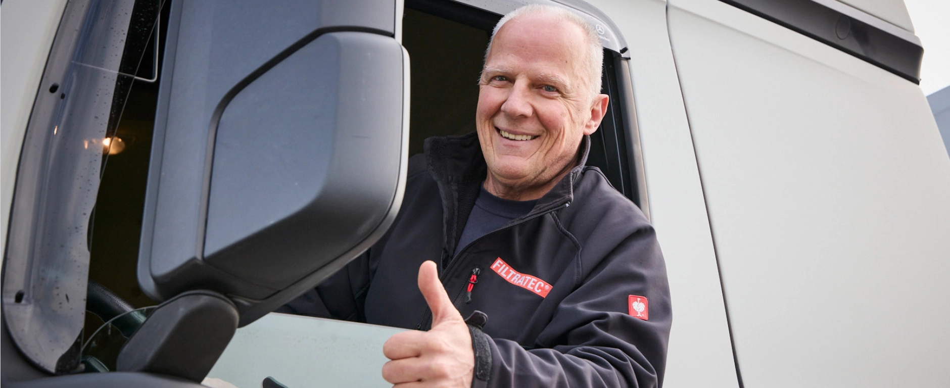 An employee in FILTRATEC gear sitting in a driver’s cab, smiling and giving a thumbs up.
