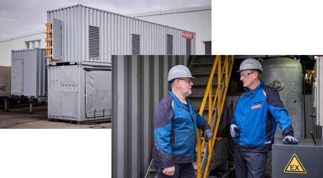 Mobile ATEX decanters on a business premises and two employees wearing protective clothing and hard hats talking to each other